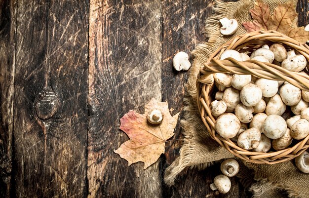 Verse champignons in een mand. Op een houten achtergrond.