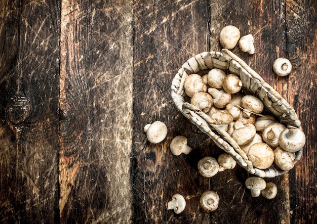 Verse champignons in een mand. Op een houten achtergrond.