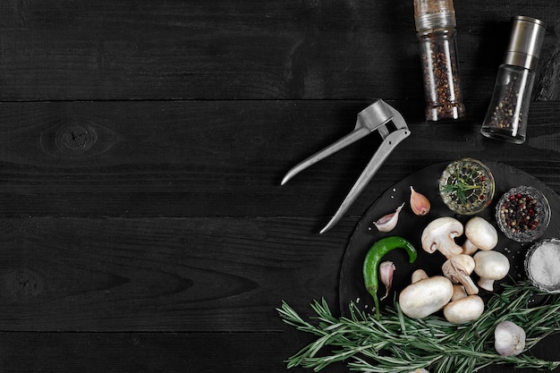 Verse champignons met specerijen en kruiden op een zwart bord op een zwarte houten achtergrond Bovenaanzicht met kopieerruimte Stilleven Plat leggen