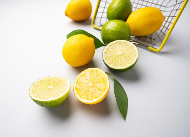 Verse citroenen en limoenen vallen uit een supermarktmand op een blauwe achtergrond Citrusvruchtenconcept voor vers geperste limonade