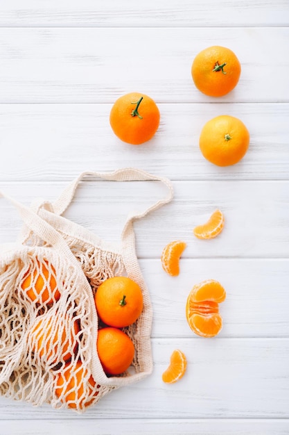 Verse clementines met bladeren op witte houten tafel.