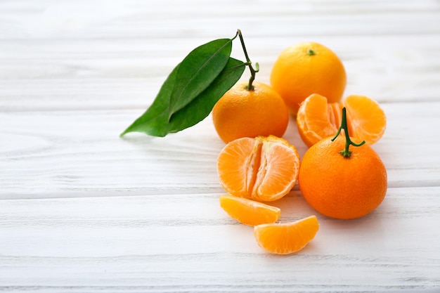 Verse clementines met bladeren op witte houten tafel.