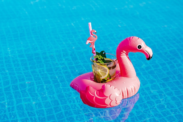 Verse coctailmojito op opblaasbaar roze flamingostuk speelgoed bij zwembad. Vakantie concept.