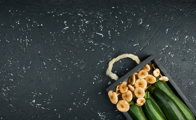 Verse courgette, champignons op een zwarte bord in bovenaanzicht met kopie ruimte