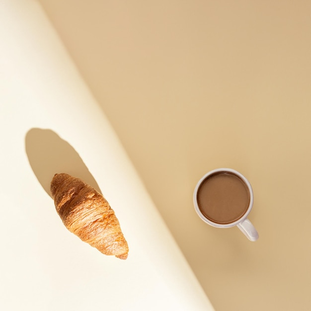 Verse croissant en kop warme koffie met melk in fel zonlicht Ontbijt op zomerochtend