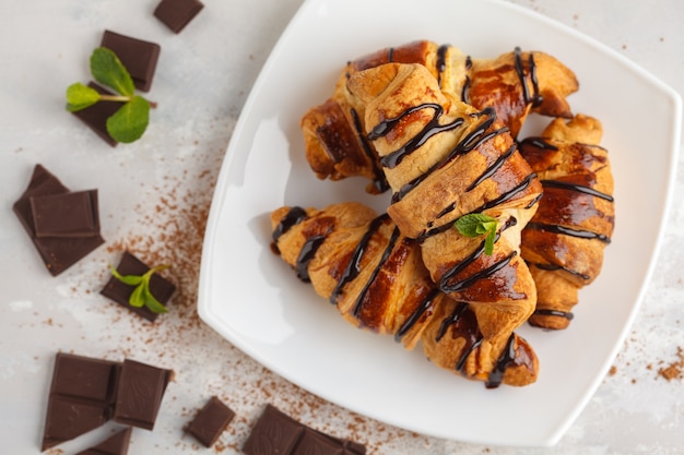 Verse croissants met chocoladesiroop op een lichte achtergrond, kopie ruimte, bovenaanzicht. Franse keuken dessert concept.