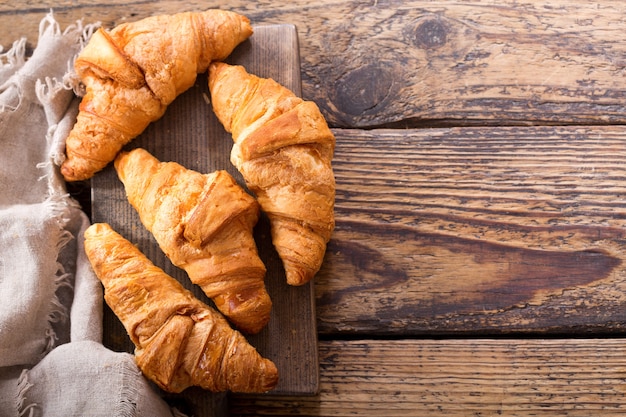 Verse croissants op een houten bord, bovenaanzicht