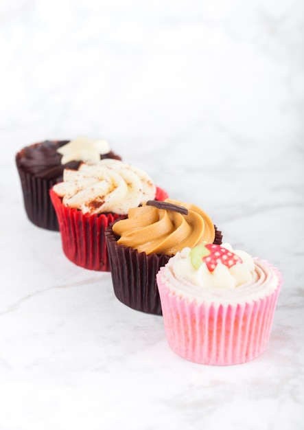 Verse cupcake muffins met karamel en chocolade, aardbeien en toffee op marmeren bord