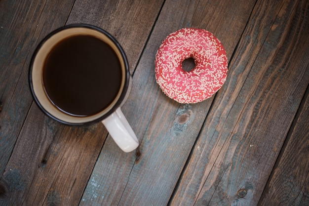 Verse donut met kopje koffie op de houten tafel