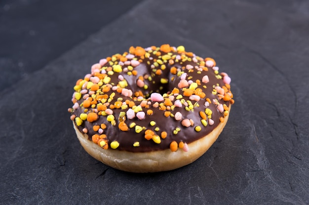 Verse donut met toppings op een donkere achtergrond.