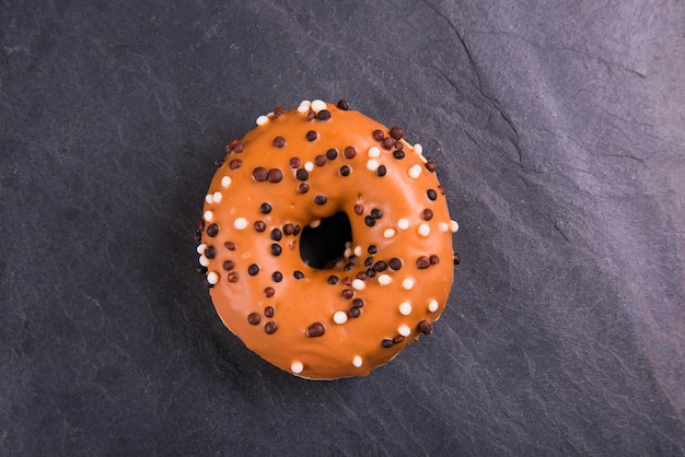 Verse donut met toppings op een donkere achtergrond.