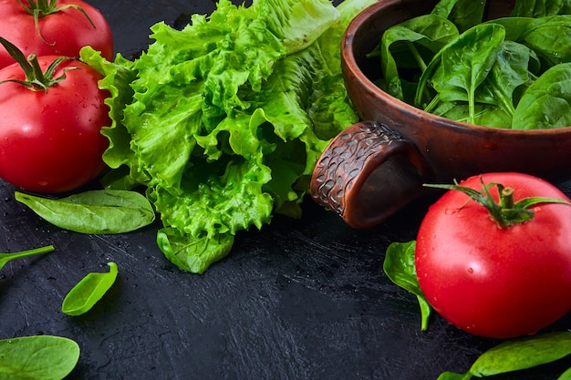 Verse druiven tomaten met salade en spinazie Bladeren op zwarte steen.