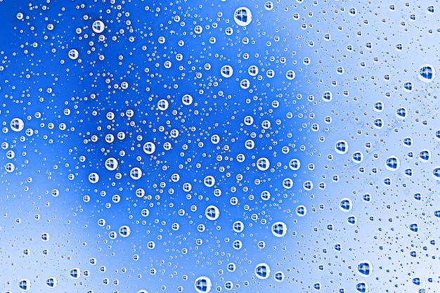 verse druppels achtergrond blauw glas / natte regenachtige achtergrond, waterdruppels transparant glas blauw