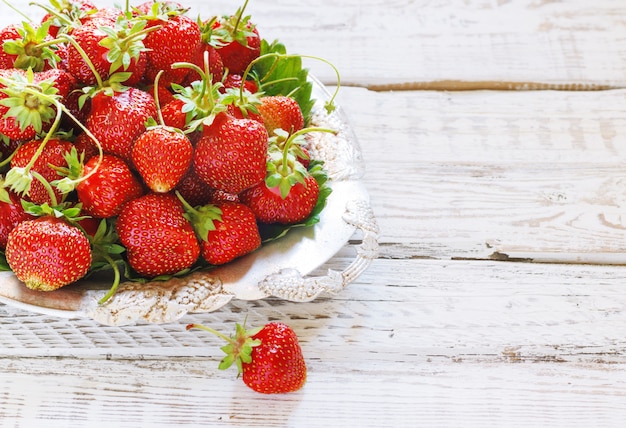 Verse en heerlijke biologische aardbeien op oude metalen plaat, houten tafel. Perfect voor uw dieet met gezond eten.