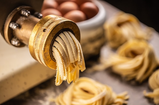 Verse fettuccine pasta die uit de pastamachine komt.