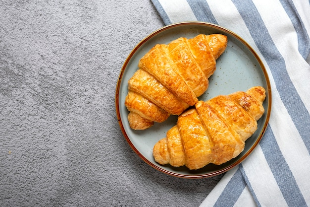 Verse Franse croissants op plaat, servet op grijze granietachtergrond