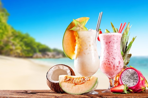 Verse fruitdranken op houten planken vervagen het strand op de achtergrond