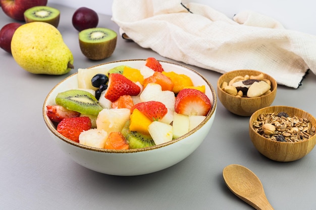 Verse fruitsalade in een kom Veelkleurig en tropisch fruit Ananas mango druif aardbei papaya meloen kiwi Extra met kastanjes en muesli Selectieve focus