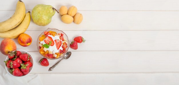 Verse fruitsalade met yoghurt in een kom met exemplaarruimte. gezond fitnessontbijt.