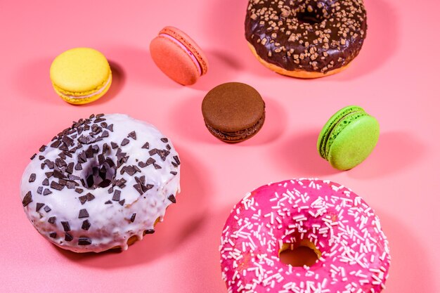 Verse geglazuurde donuts en Franse bitterkoekjes geïsoleerd op een roze achtergrond