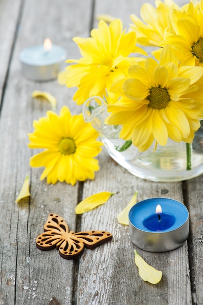 Verse gele madeliefjebloemen, vlinder en aangestoken kaars