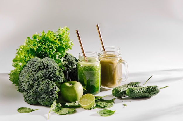 Verse gemengde groene smoothie in pot op witte tafel. Detox en dieet concept. Vegetarisch eten.