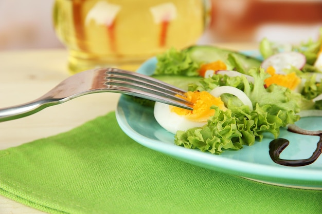 Verse gemengde salade met de bladeren van de eierensalade en andere groenten op kleurenplaat op lichte achtergrond