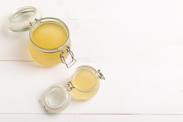 Foto verse gevogeltebouillon in een glazen pot op een witte tafel. bovenaanzicht met kopieerruimte