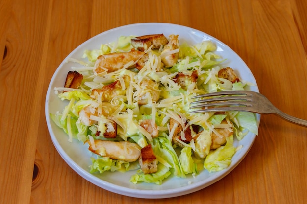 Verse gezonde caesar salade met kip borst sla parmesan kaas dressing en croutons op houten tafel