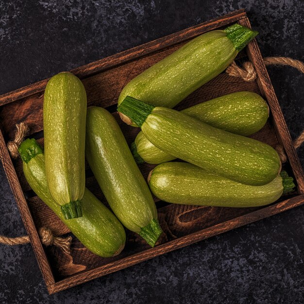 Verse gezonde groene courgette courgettes in bruine houten doos