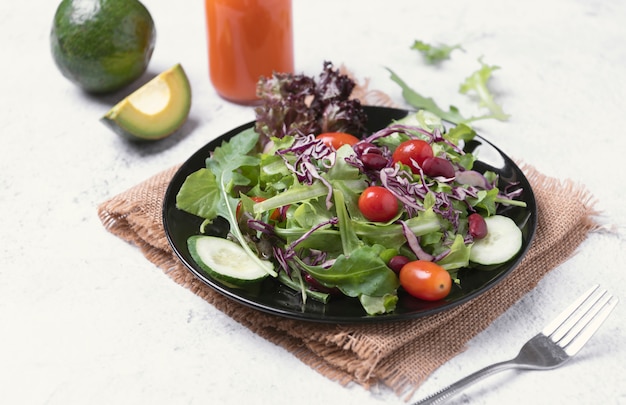 Verse gezonde groentesalade met tomaat, komkommer, spinazie, sla in plaat op tafel.
