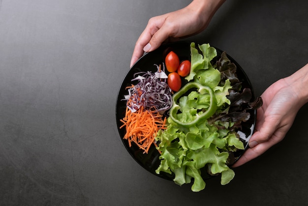 Verse gezonde groentesalade met tomaat, wortel, spinazie, sla in plaat op tafel