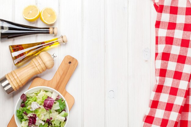 Verse gezonde salade en specerijen over witte houten tafel