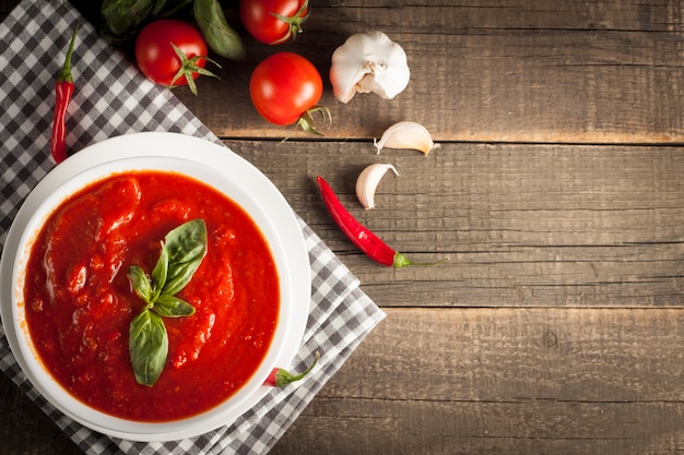 Verse, gezonde tomatensoep met basilicum, tomaten op houten achtergrond. Spaanse gazpacho-soep.