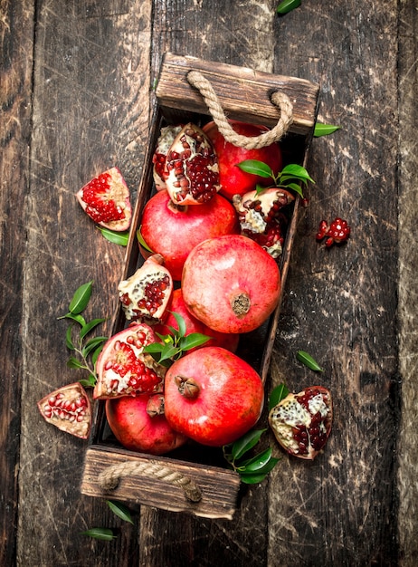 Verse granaatappels in een oude doos op een houten achtergrond