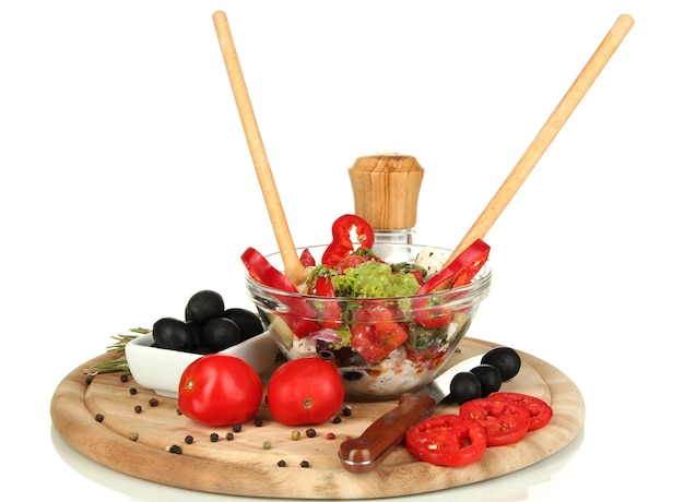 Verse Griekse salade in glazen kom omringd door ingrediënten voor het koken geïsoleerd op wit