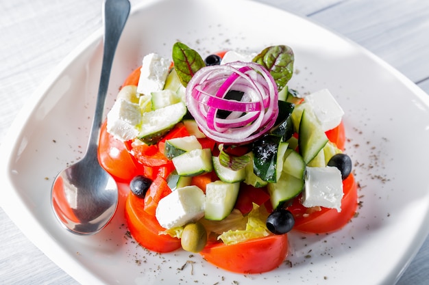 Verse Griekse salade op witte plaat met ui