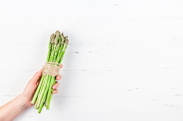 Verse groene asperges in handen van de vrouw