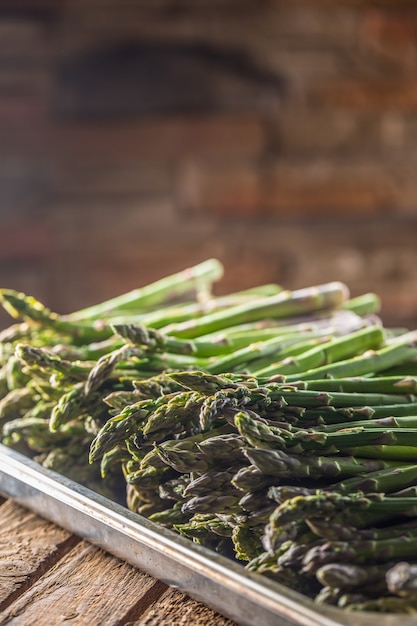 Verse groene asperges liggend op een houten kist.