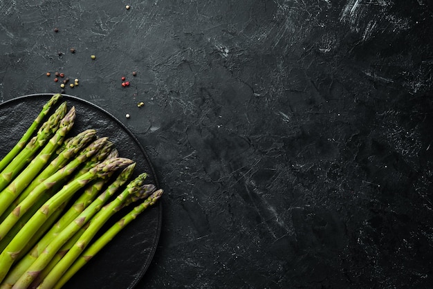 Verse groene asperges op een zwarte stenen achtergrond Bovenaanzicht Vrije ruimte voor uw tekst