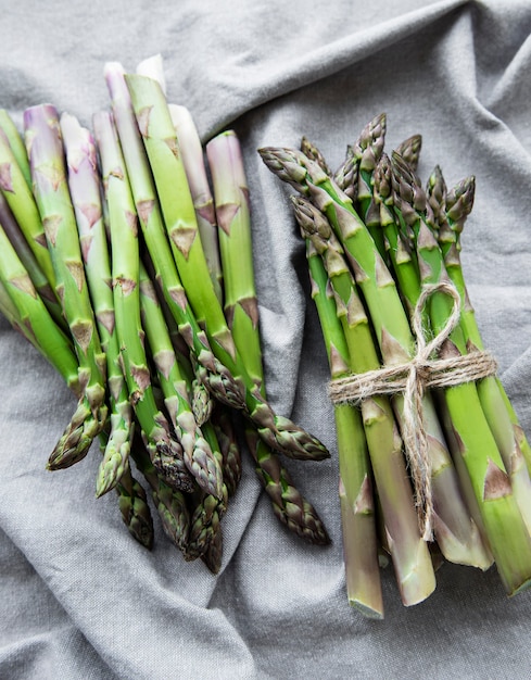 Verse groene asperges op grijze textieloppervlakte