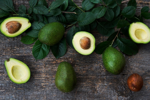 Verse groene avocado met bladeren op houten ruimte