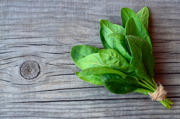 Verse groene biologische spinazie bundel bladeren op oude houten tafel. Gezond eten, detox, dieet voedselingrediënt concept.