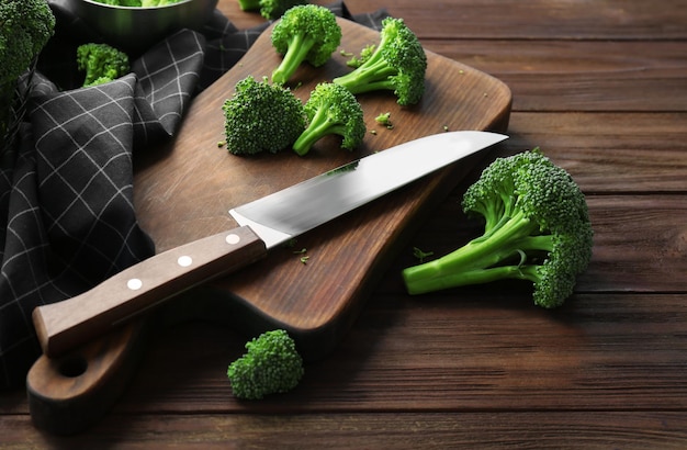 Verse groene broccoli en mes op een houten bord