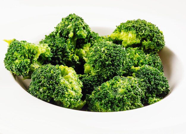 Verse groene broccoli in witte cirkelplaat die op wit wordt geïsoleerd