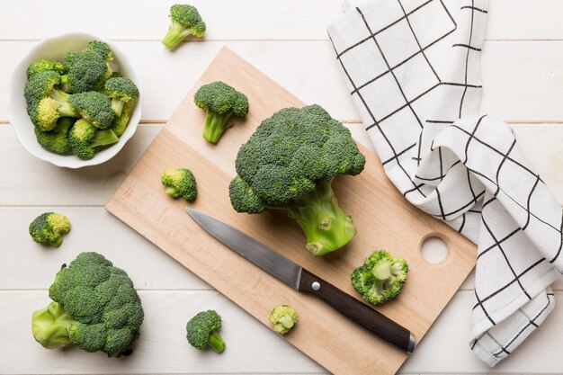 Verse groene broccoli op houten snijplank met mes. Broccoli koolbladeren. lichte achtergrond. Plat leggen.