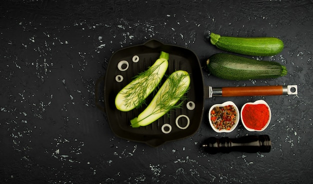 Verse groene courgette in een pan op een donkere tafel. Het uitzicht vanaf de top. Kopieer ruimte.