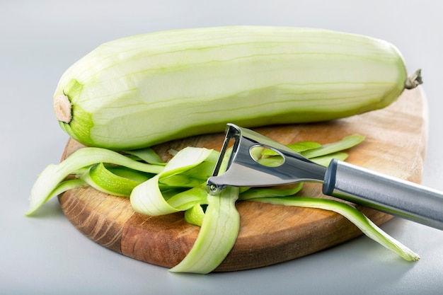 Verse groene courgette pellen met dunschiller. Proces van het schoonmaken van rauwe pompoen met een dunschiller.