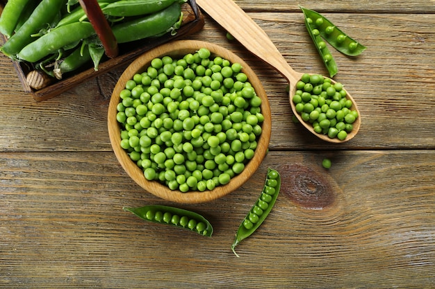 Verse groene erwten in kom en lepel op tafel close-up