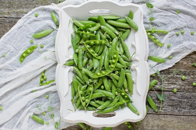 Verse groene erwten op een wit houten dienblad op een houten rustieke achtergrond